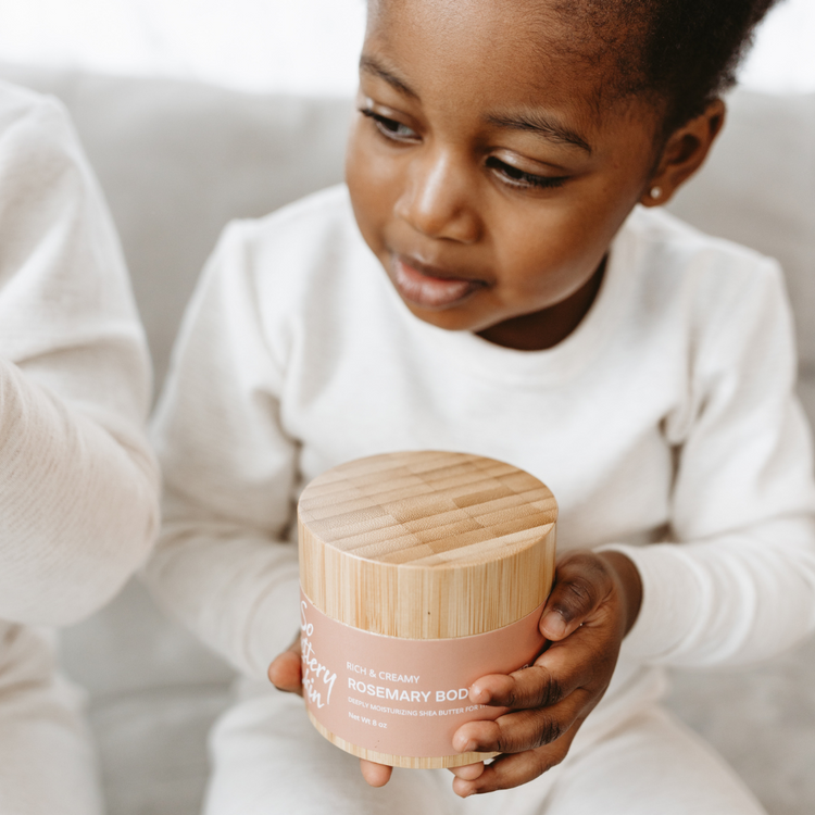 Little girl holding Jar of plant-based rosemary body butter