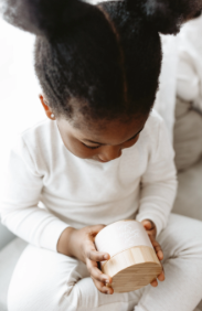 Young child holding a jar of So Buttery Skin organic, plant-based body butter with a sustainable bamboo lid